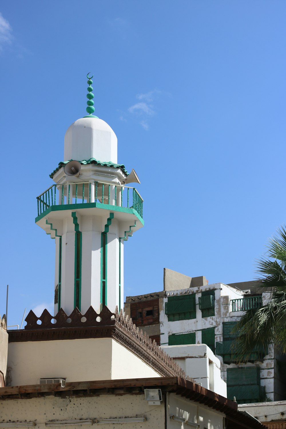 a tall white and green building with a green roof