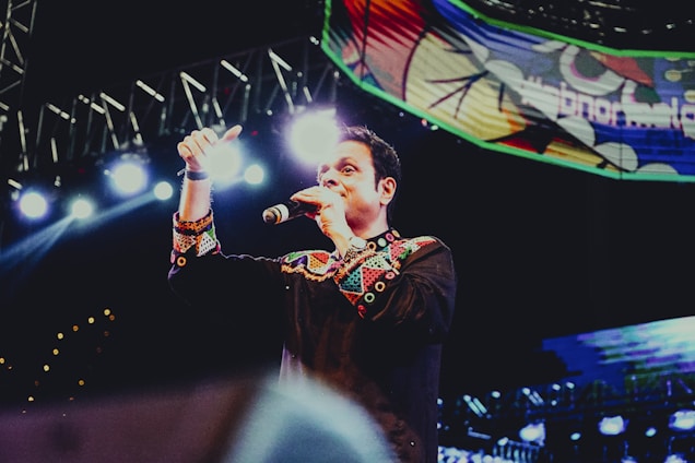 A charismatic Dominican artist performing on stage with a microphone.