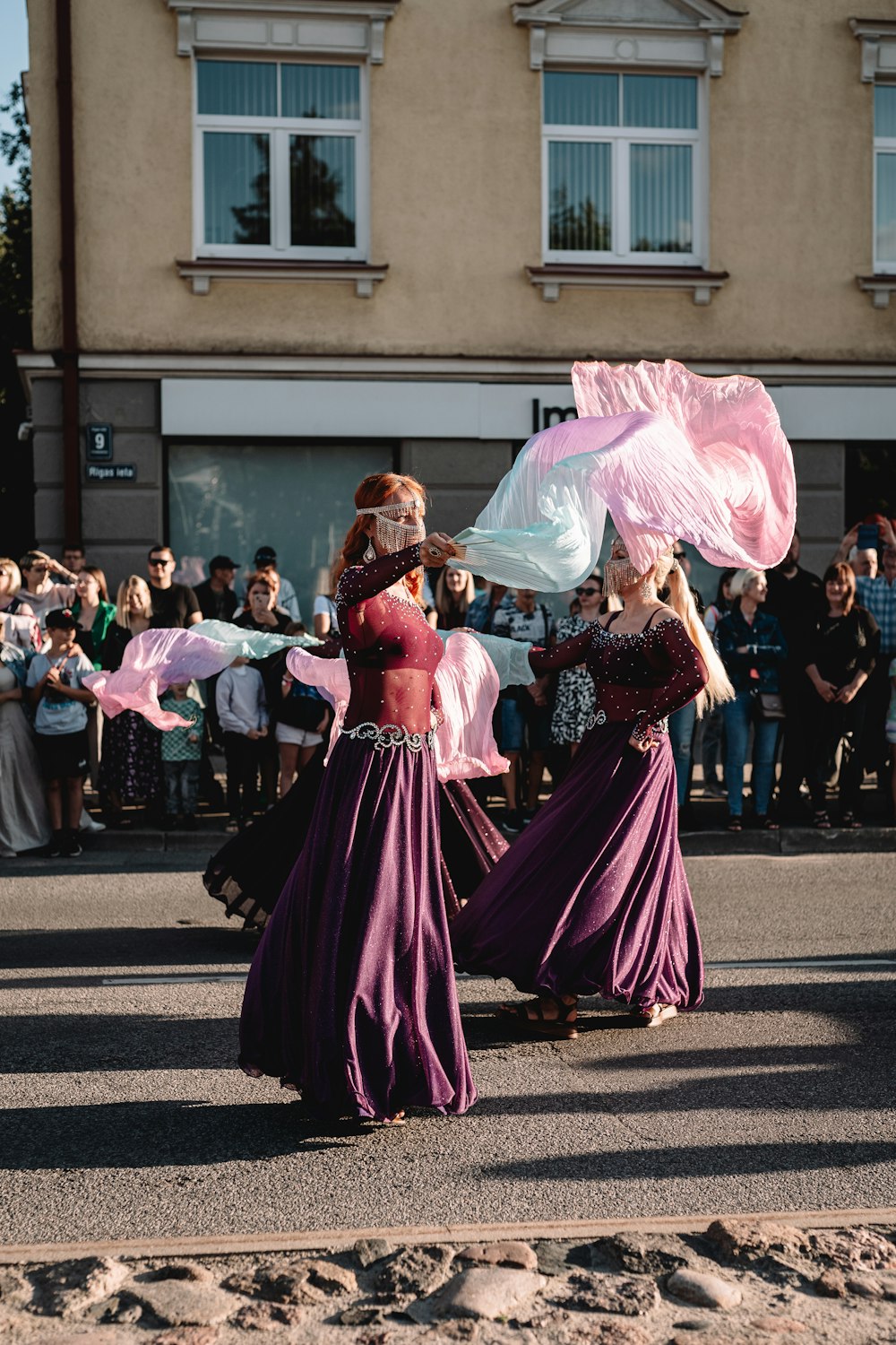 two women in long dresses are walking down the street