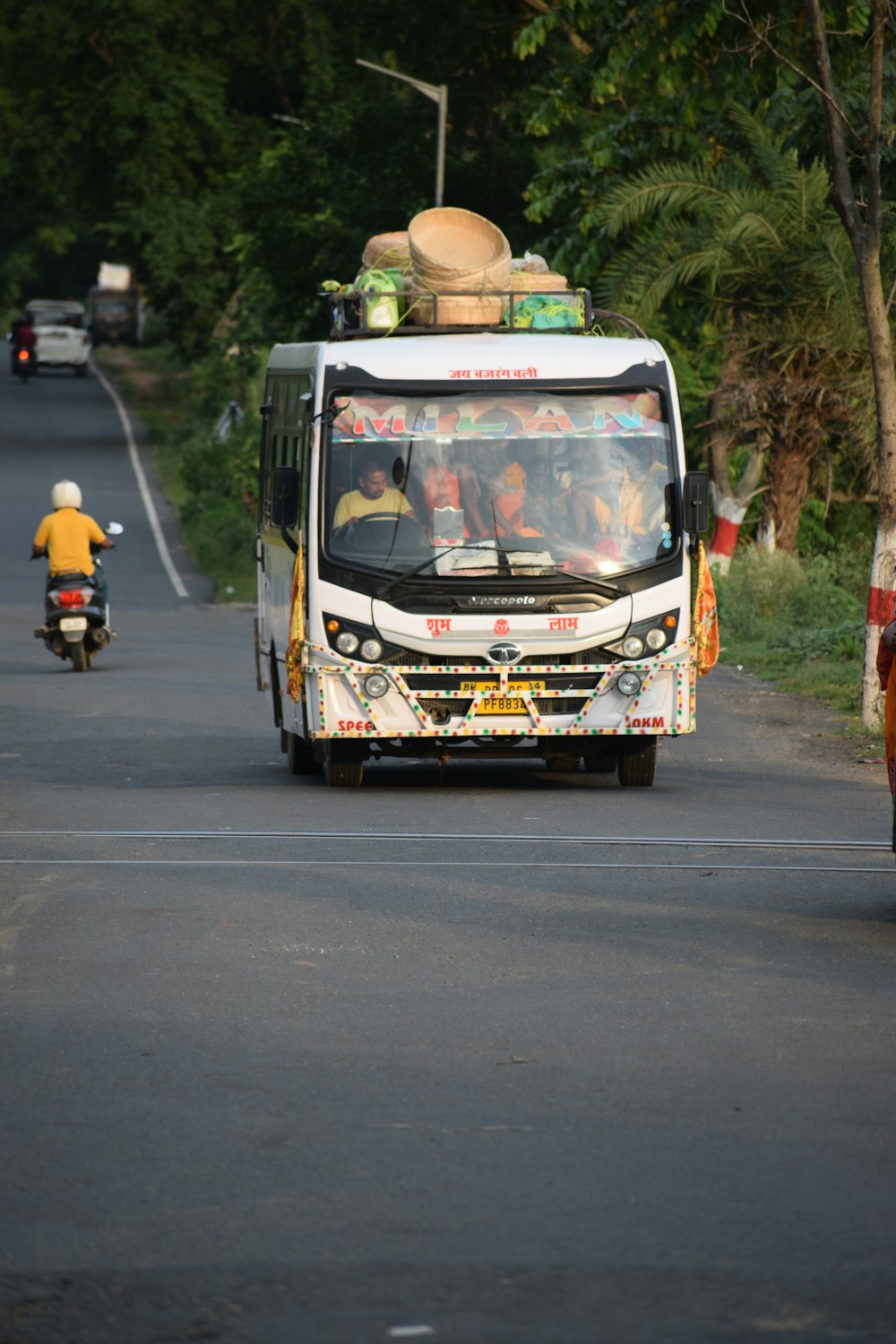 a white bus driving down a street next to a forest