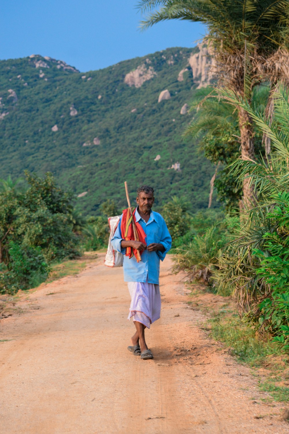 a man is walking down a dirt road