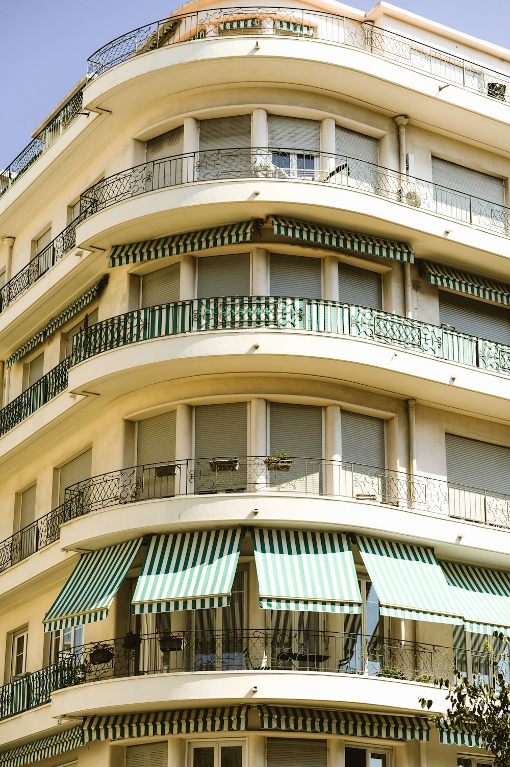 a tall building with balconies and green awnings