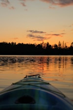 A vibrant sunrise over Samaná Bay with a kayak gliding through calm waters.