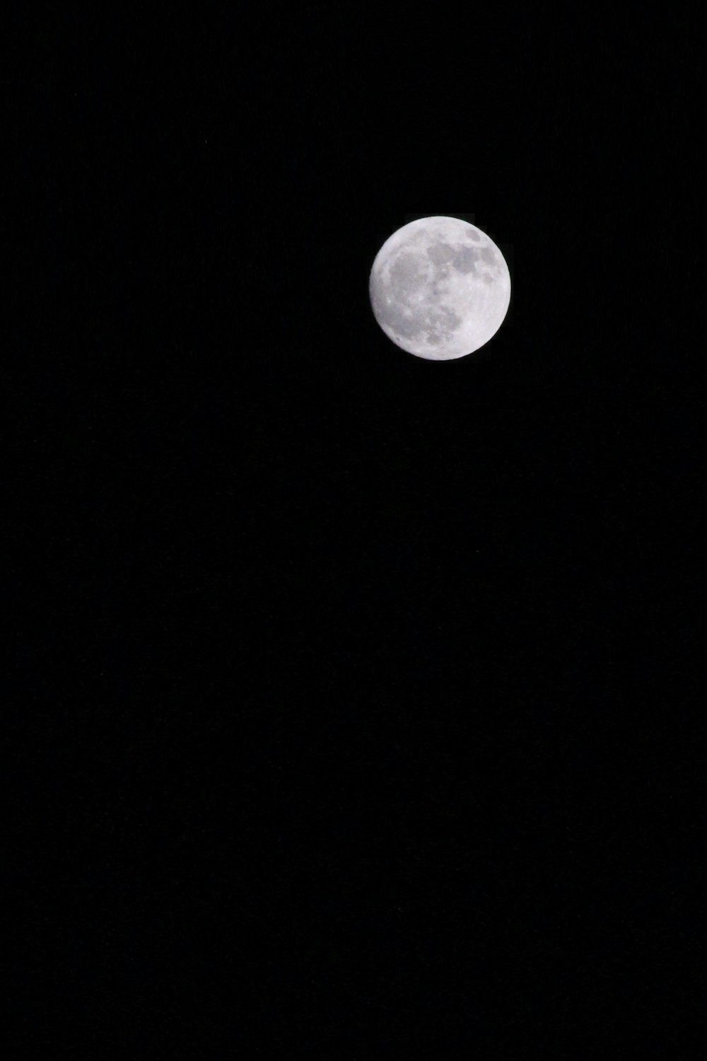 a full moon is seen in the dark sky