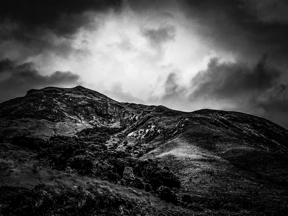 a black and white photo of a mountain under a cloudy sky