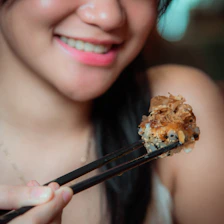 A cheerful teenage boy holding a sushi roll with a swift bird flying nearby.