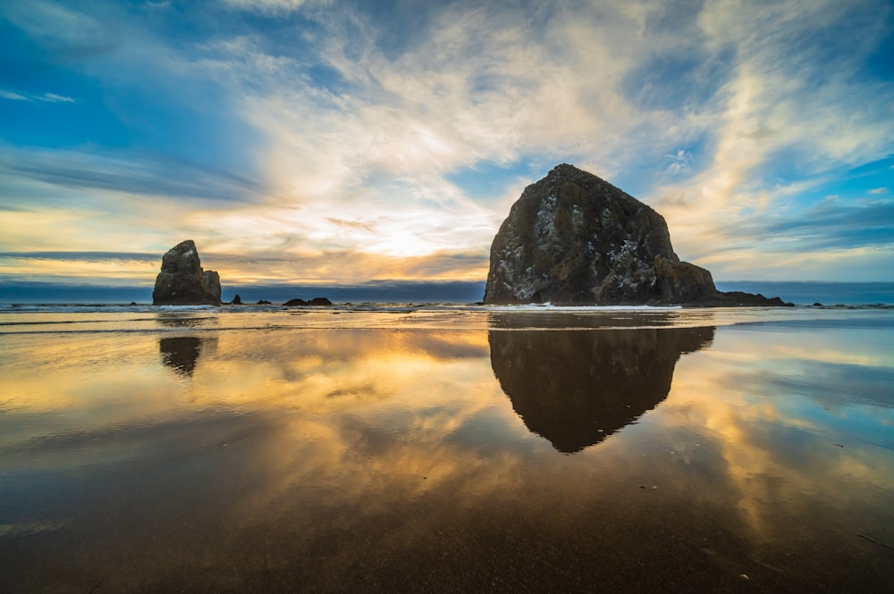 a large rock sitting on top of a beach next to the ocean