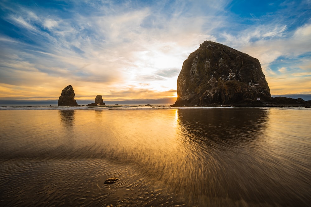 a large rock sitting on top of a sandy beach