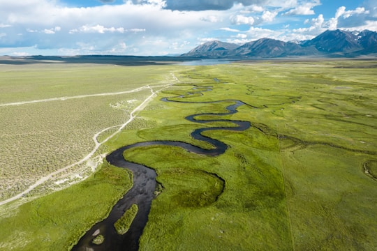 A sweeping aerial view of a lush valley with a winding river under a clear blue sky.