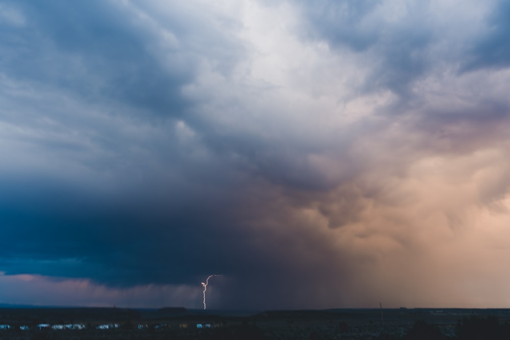 a storm moving across a cloudy sky with a lightning bolt in the distance