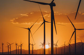 the sun is setting behind a group of windmills