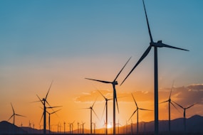 a group of windmills are silhouetted against a sunset