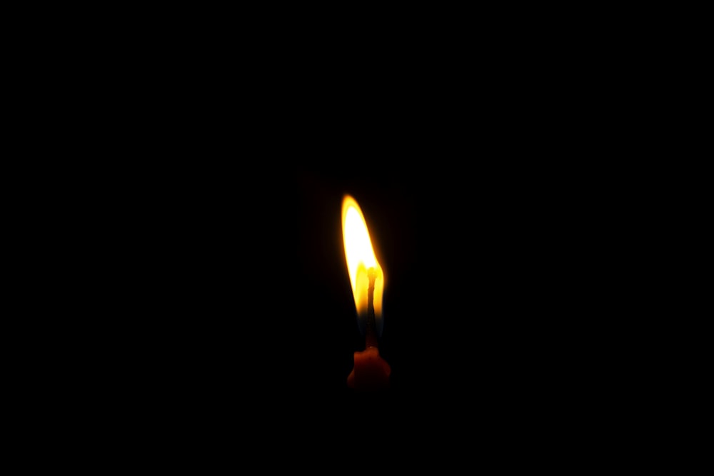 uma única vela é acesa no escuro