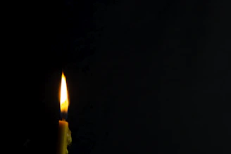 Minimalist black and white photo of a wickless candle glowing softly on a wooden table.