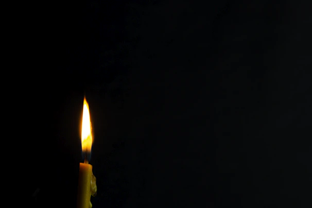 Minimalist black and white photo of a wickless candle glowing softly on a wooden table.