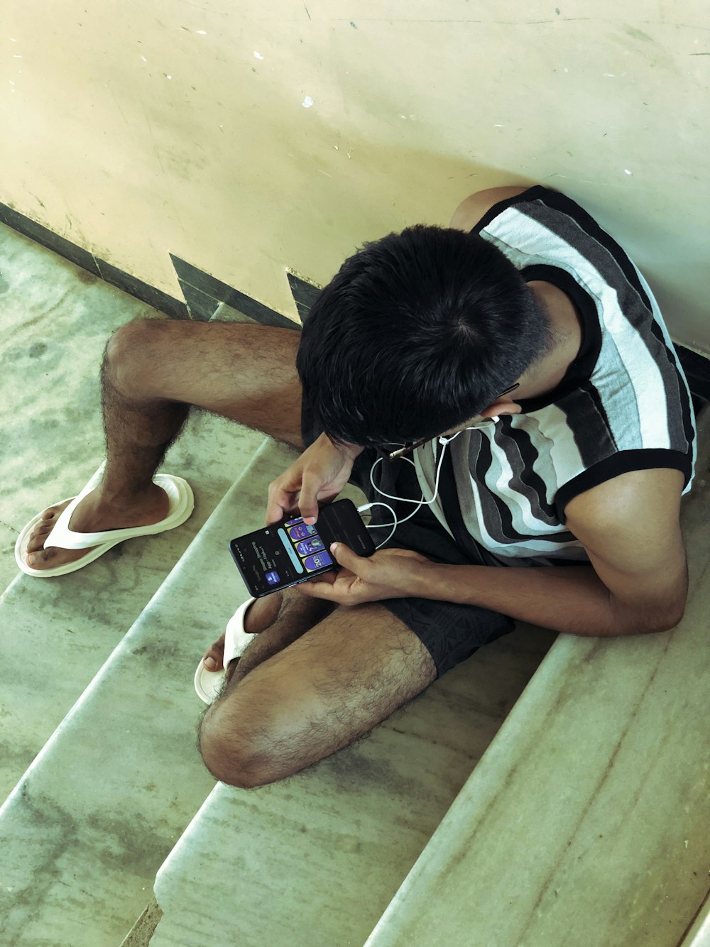 a man sitting on the floor looking at his cell phone