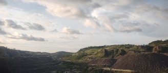 A vibrant landscape showing a mining site adjacent to lush farmland under a clear sky.