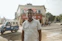 Smiling man standing next to his shiny car after a doorstep wash in Chennai.