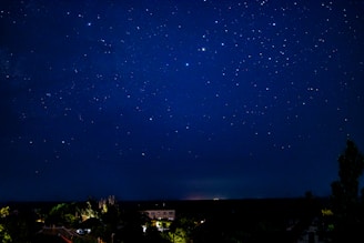 A starry night sky with constellation lines softly glowing above a quiet landscape.