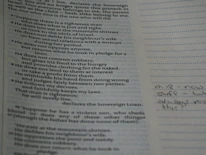Close-up of hands writing hafalan notes beside a glowing Quran.
