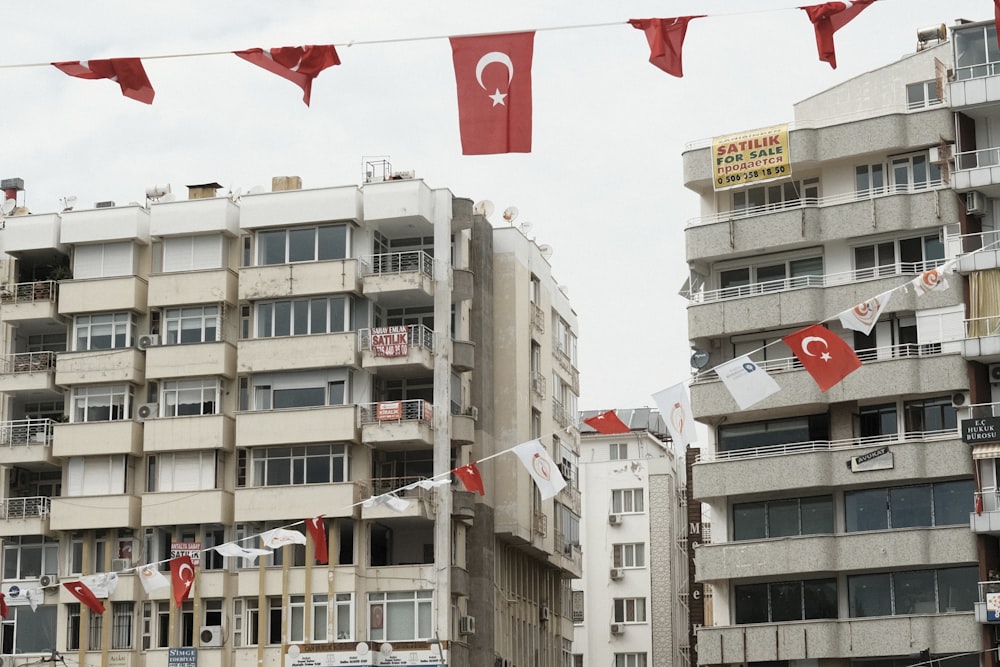 a group of flags hanging from a line in front of a building