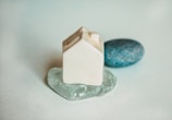 A delicate miniature ceramic house on a soft wooden table.
