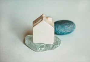 A delicate miniature ceramic house on a soft wooden table.