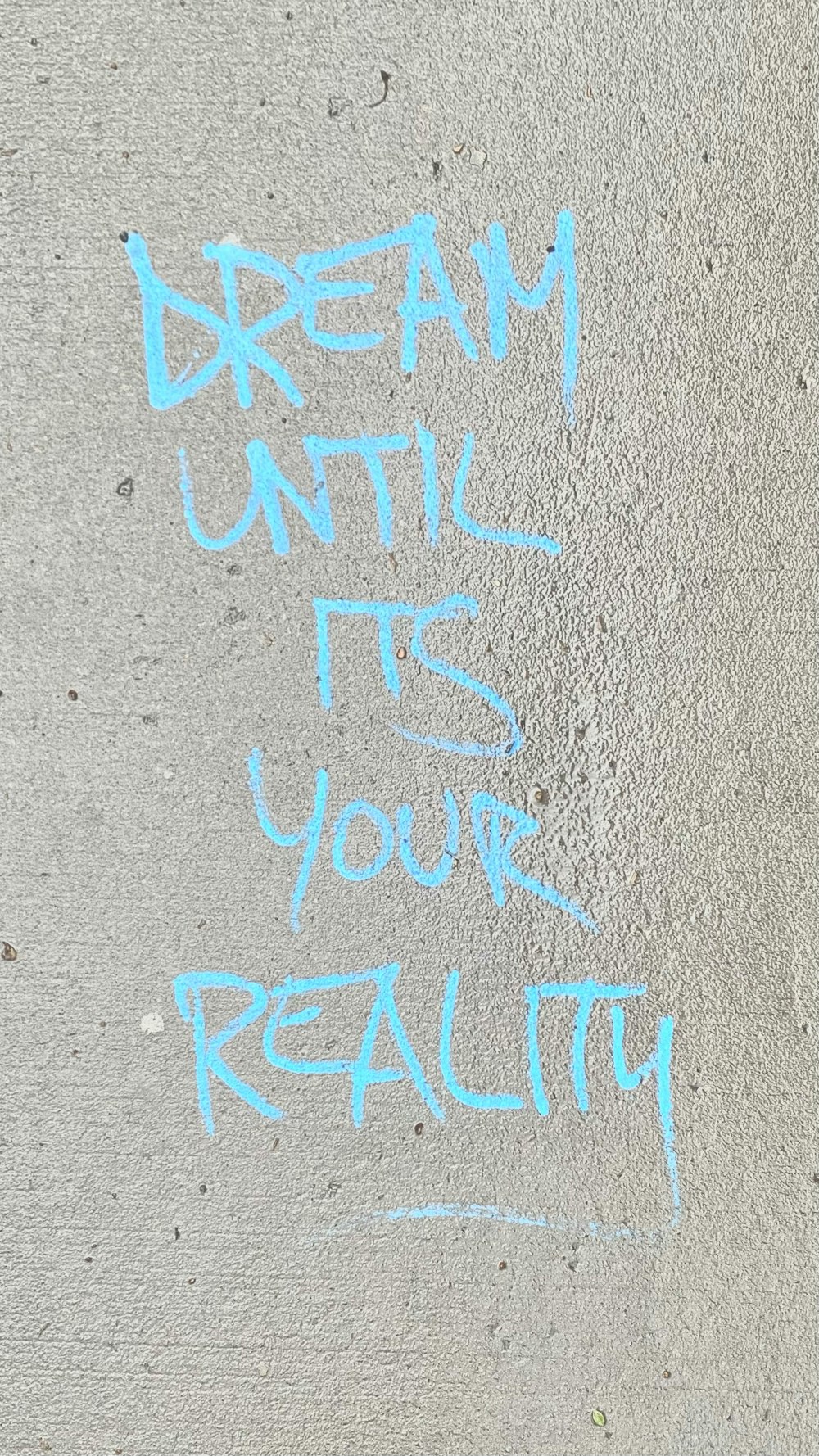 graffiti written on the side of a building says dream until it's your reality