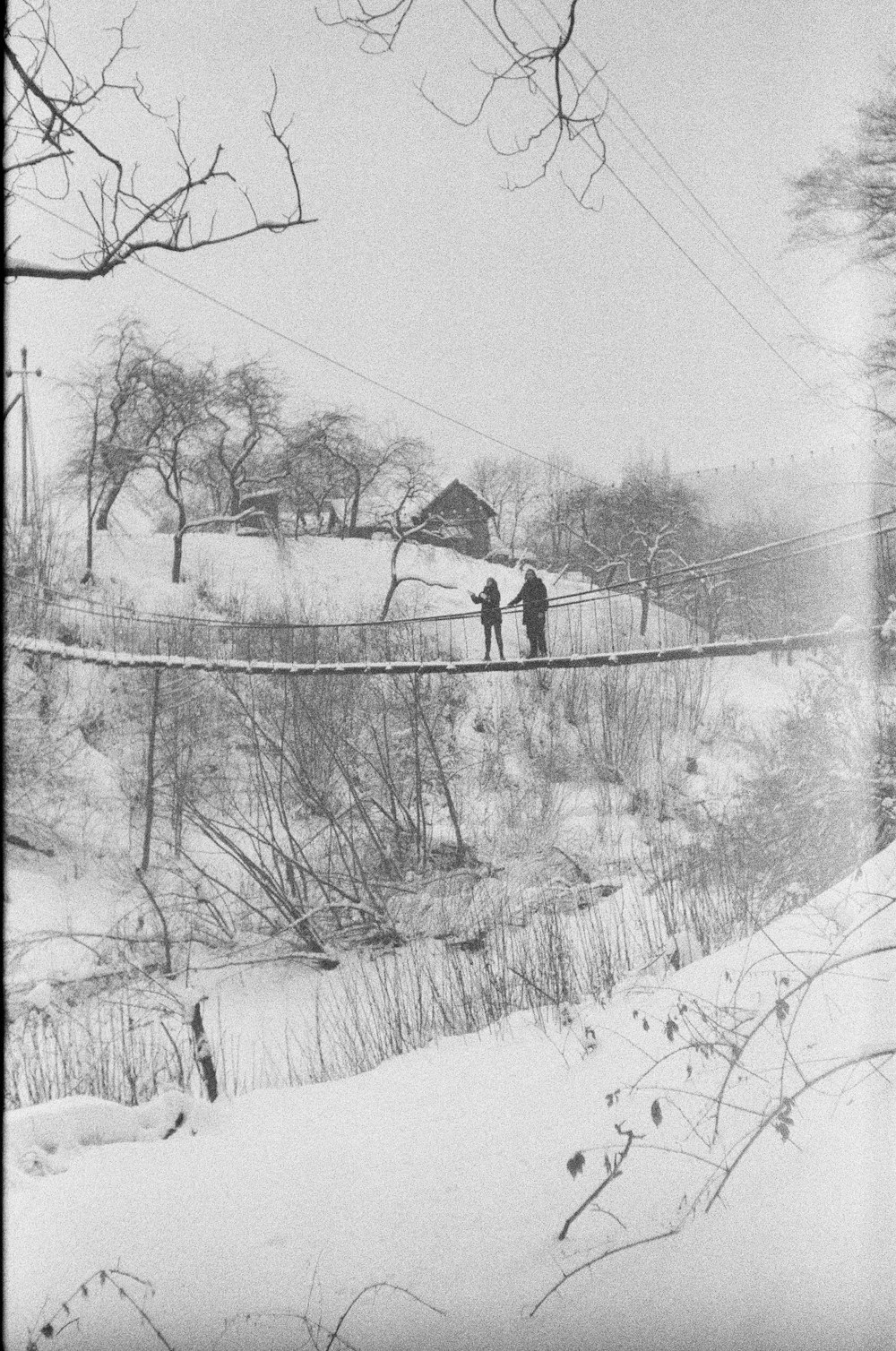 a couple of people walking across a snow covered bridge