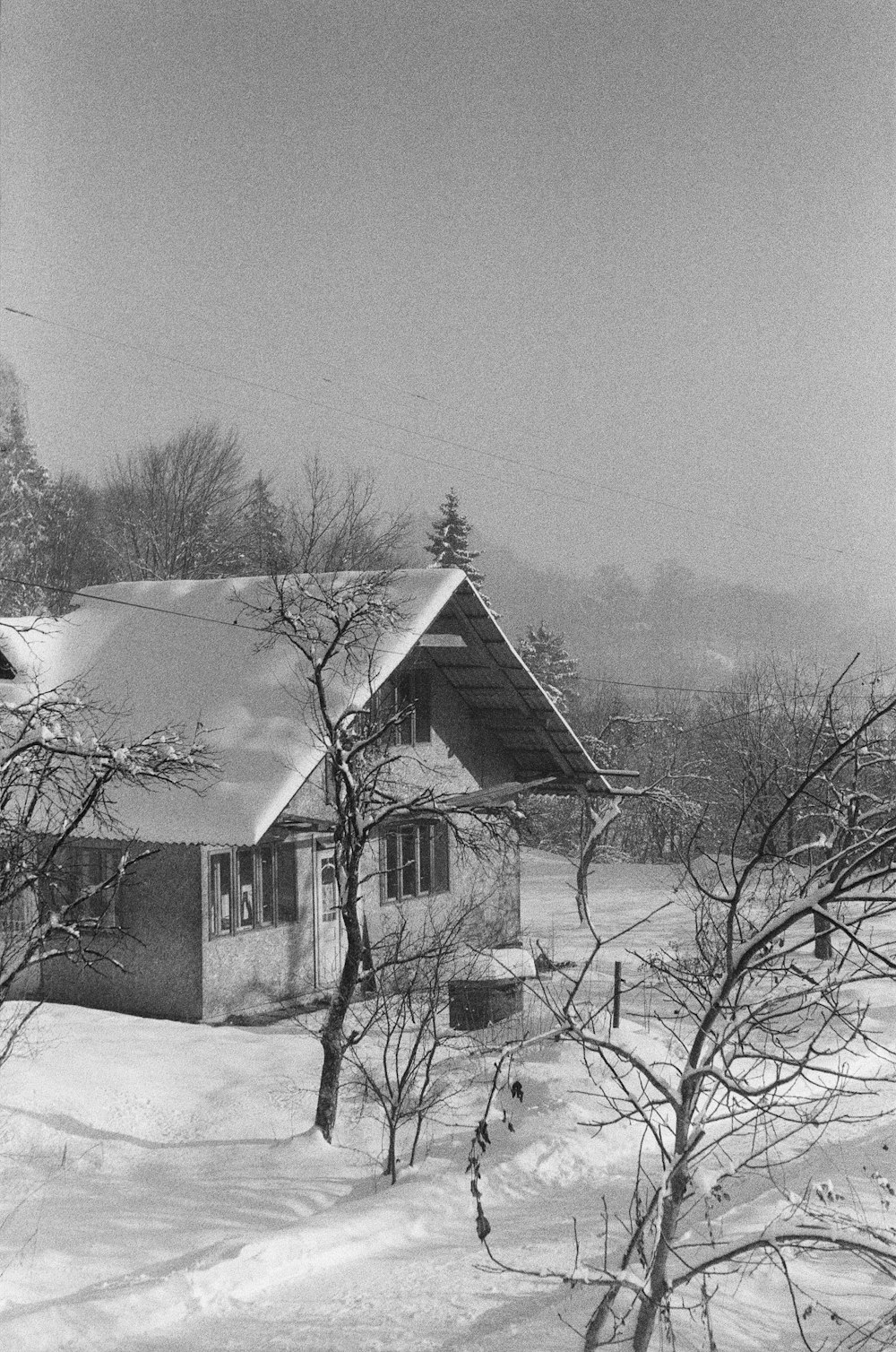 a black and white photo of a house in the snow