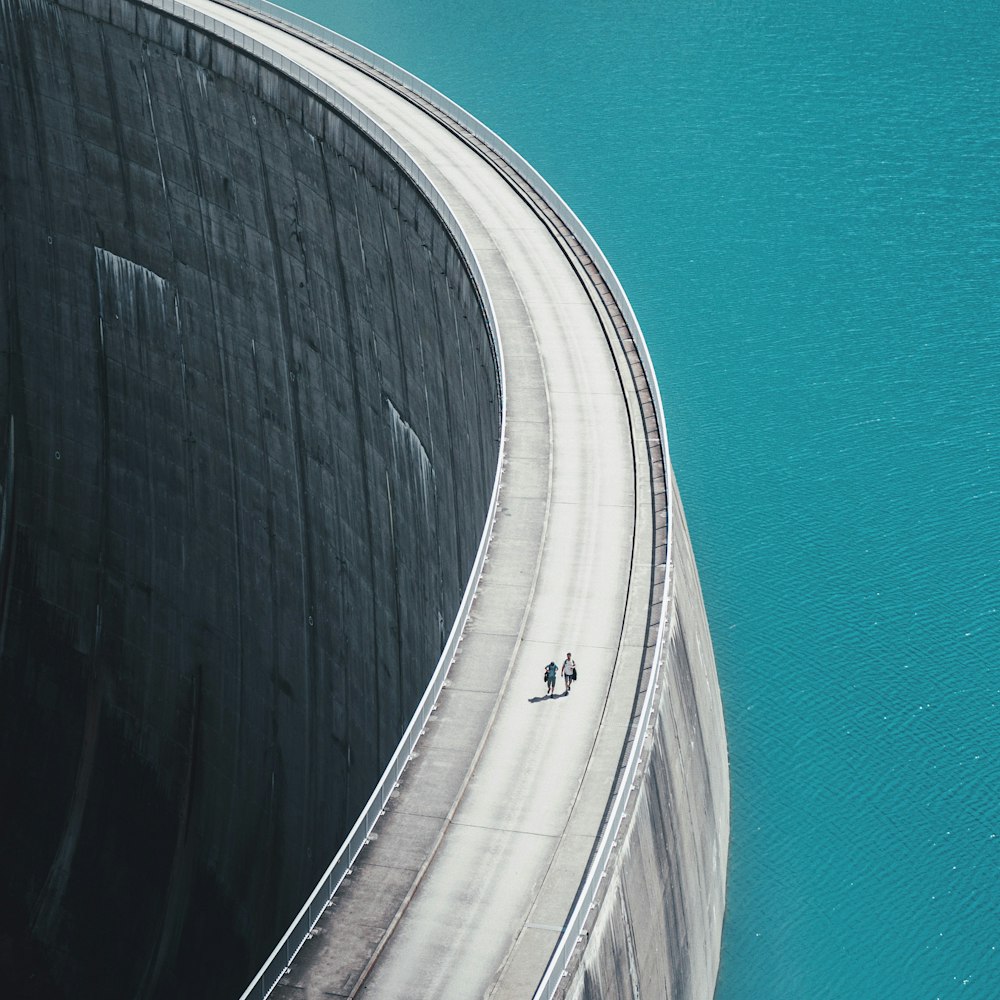 two people walking on a bridge over a body of water