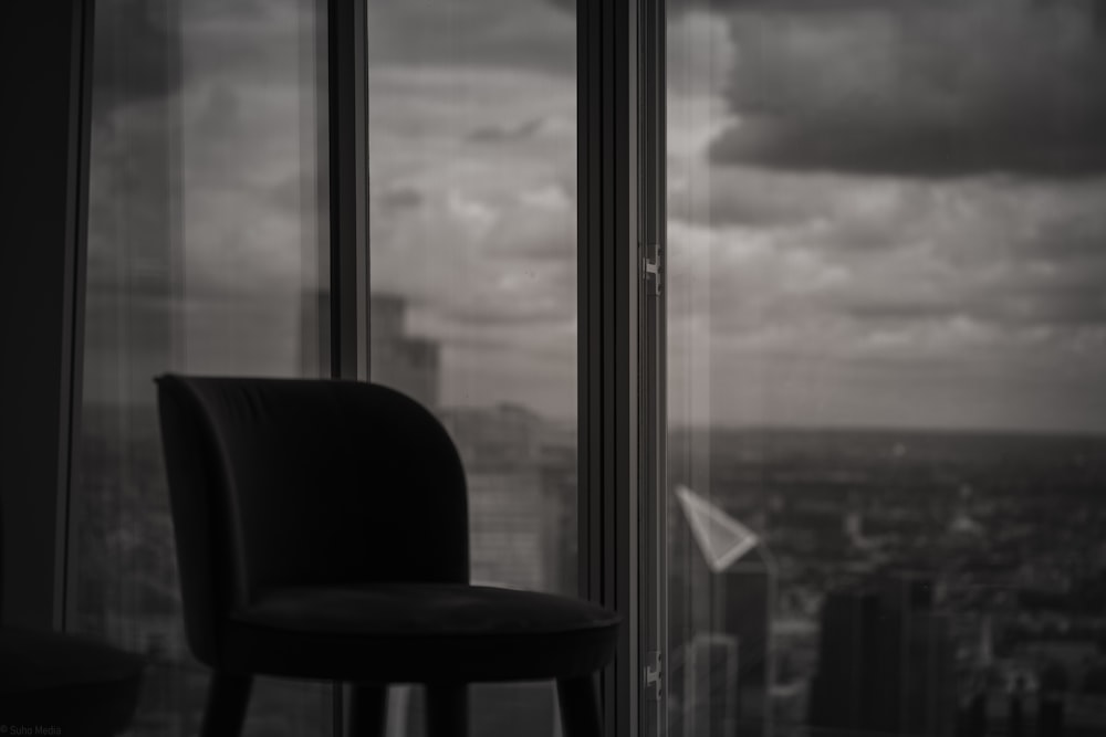 uma foto em preto e branco de uma cadeira e uma janela