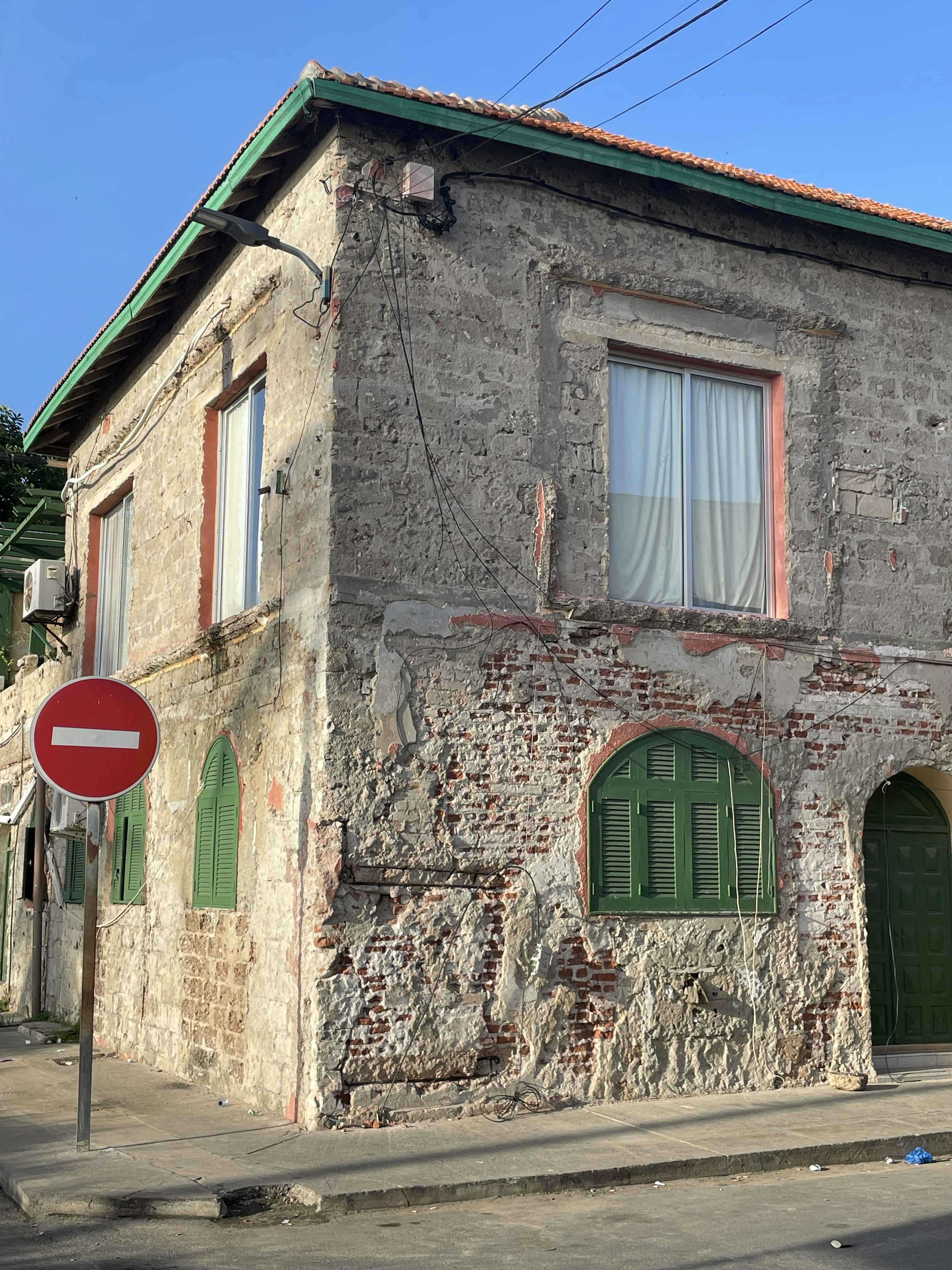 a brick building with green shutters and a stop sign