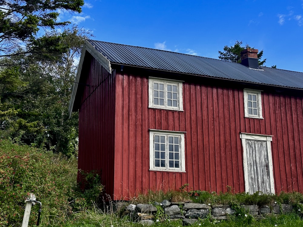 a red barn with a black roof and windows