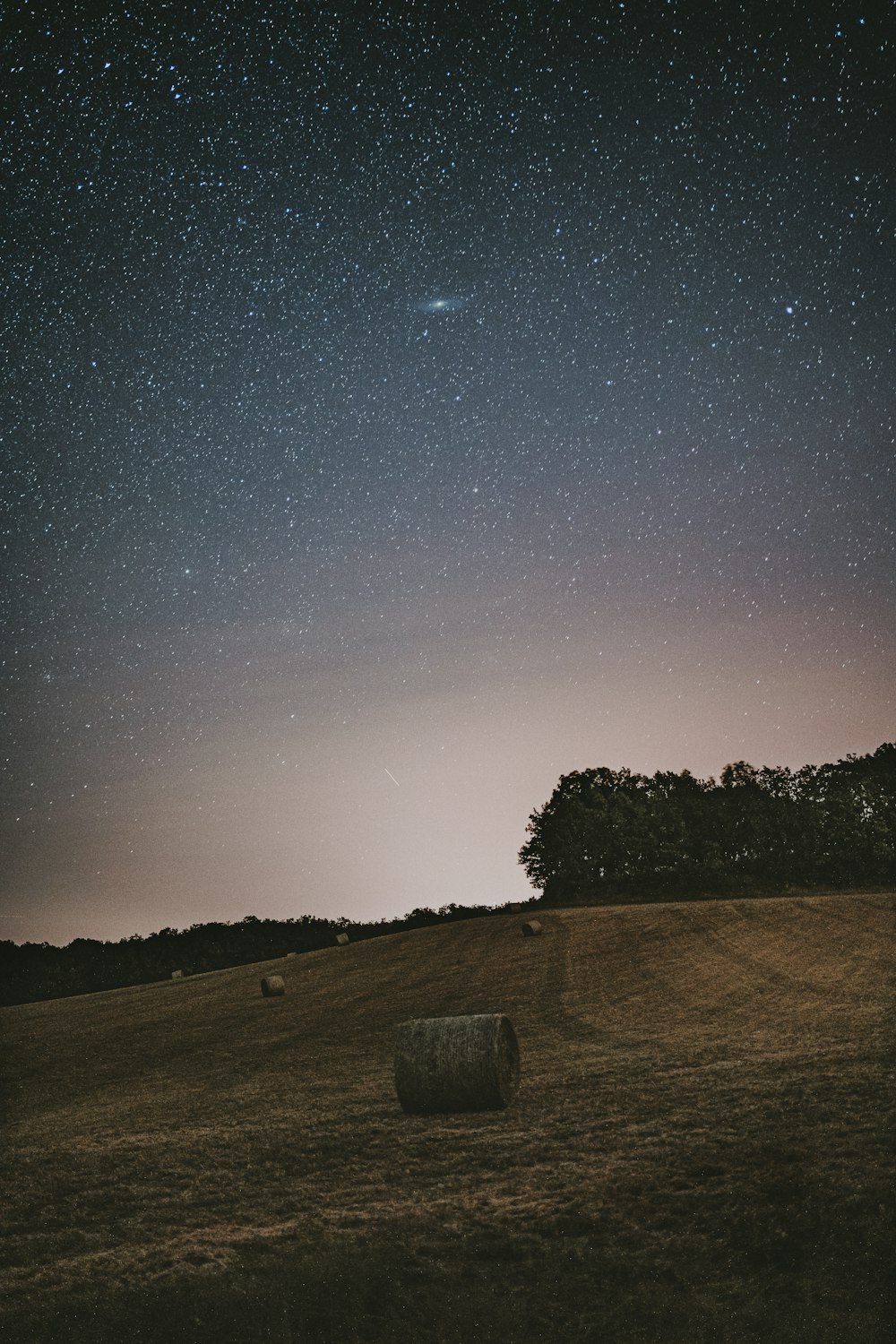 a field with hay bales under a night sky