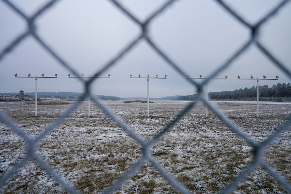 a snowy field behind a fence with power lines in the distance
