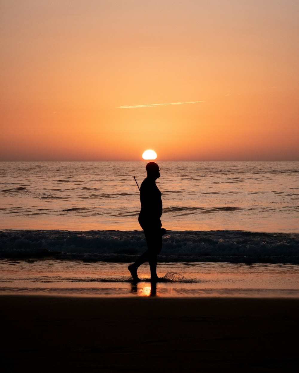 a person walking on the beach at sunset