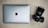 A silver laptop with an Apple logo is placed on a wooden surface next to a black Sony camera with a large lens.