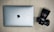 A silver laptop with an Apple logo is placed on a wooden surface next to a black Sony camera with a large lens.