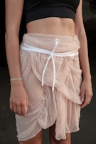 A pastel pink skirt with delicate pleats laid out on a vintage table.