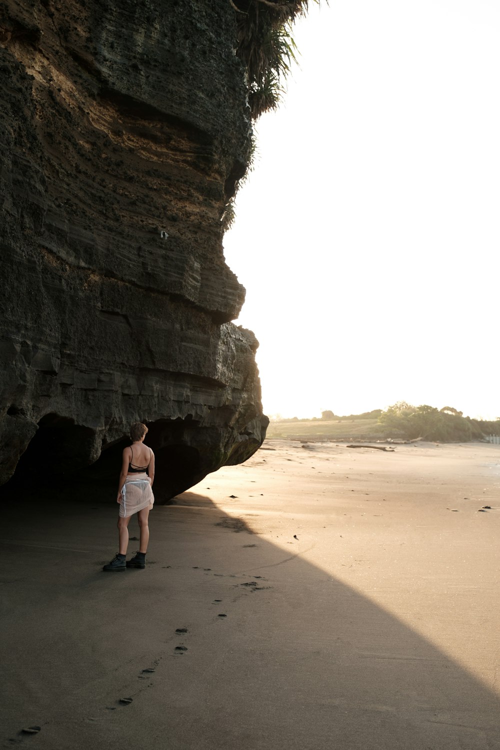 a person standing on a beach next to a cliff