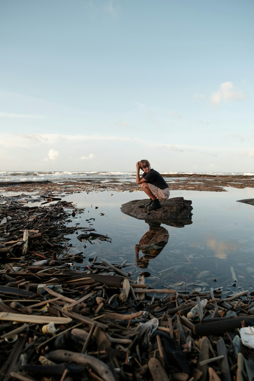 a woman sitting on a rock in the middle of a body of water