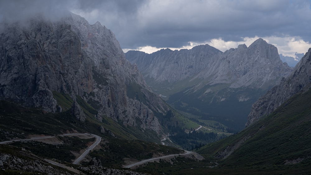 a road winding through a valley with mountains in the background