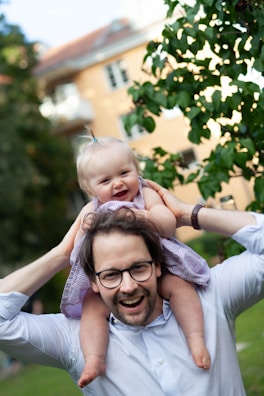 A joyful mother balancing her child on her shoulders while studying financial materials.