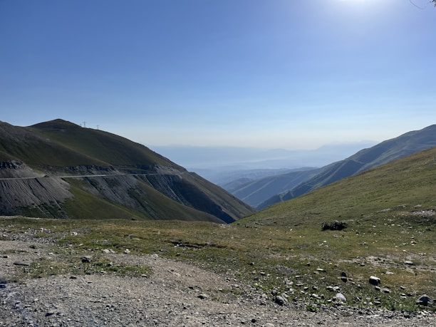A serene landscape featuring a winding road leading to distant mountains under a clear blue sky.