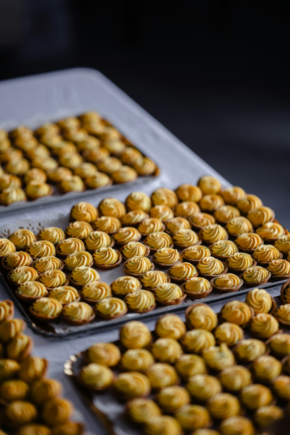 a table topped with trays of cookies covered in frosting