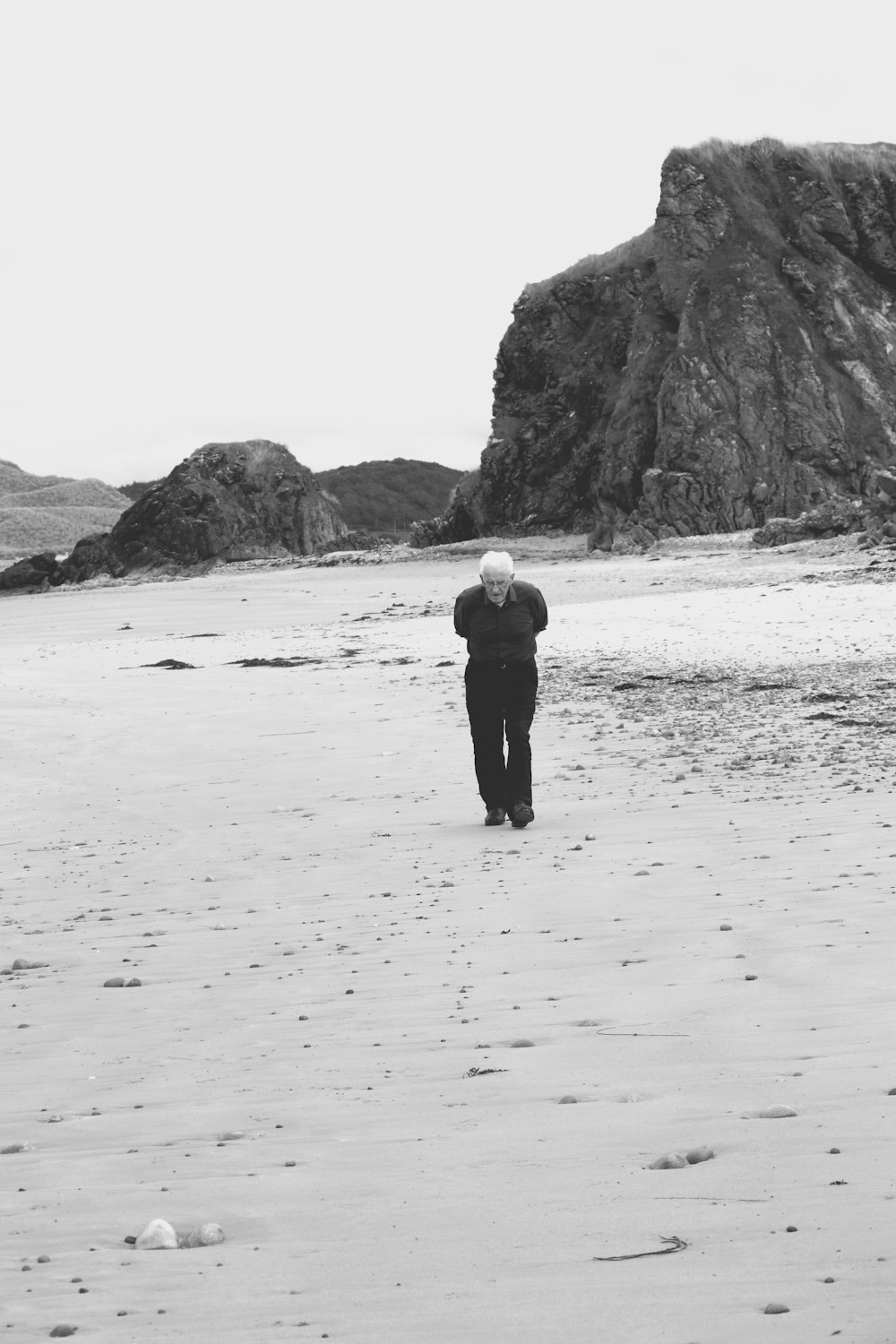 a black and white photo of a person walking on a beach