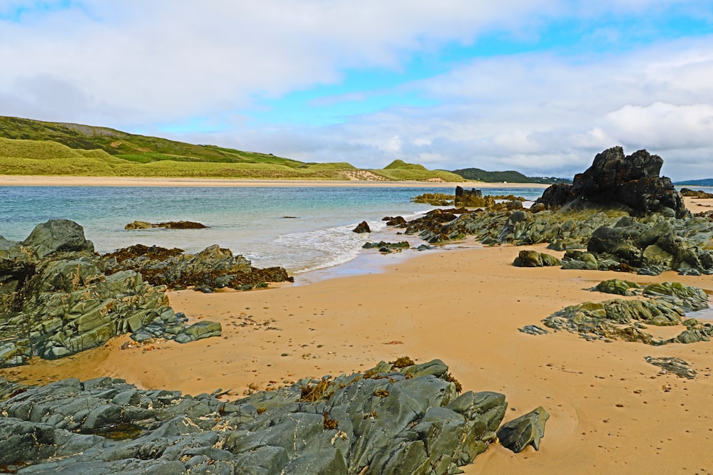 a beach with rocks and water on a cloudy day