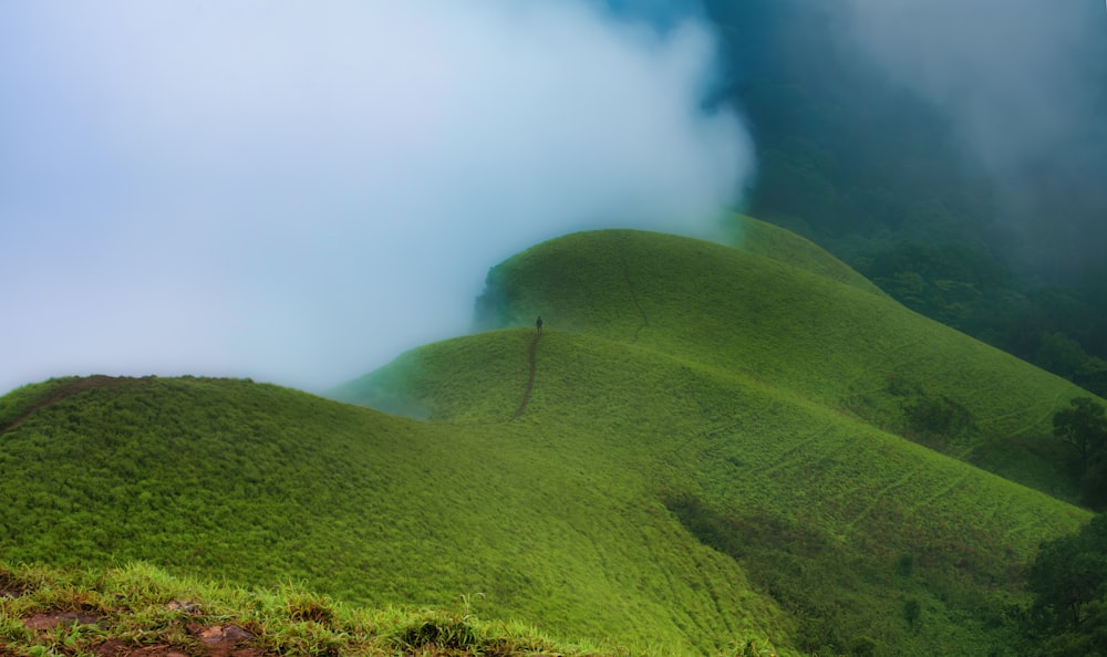 a hill covered in green grass under a blue sky