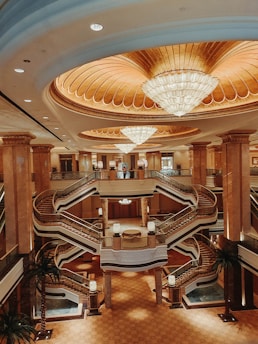 A grand hotel lobby featuring expansive marble flooring and decorative stone walls